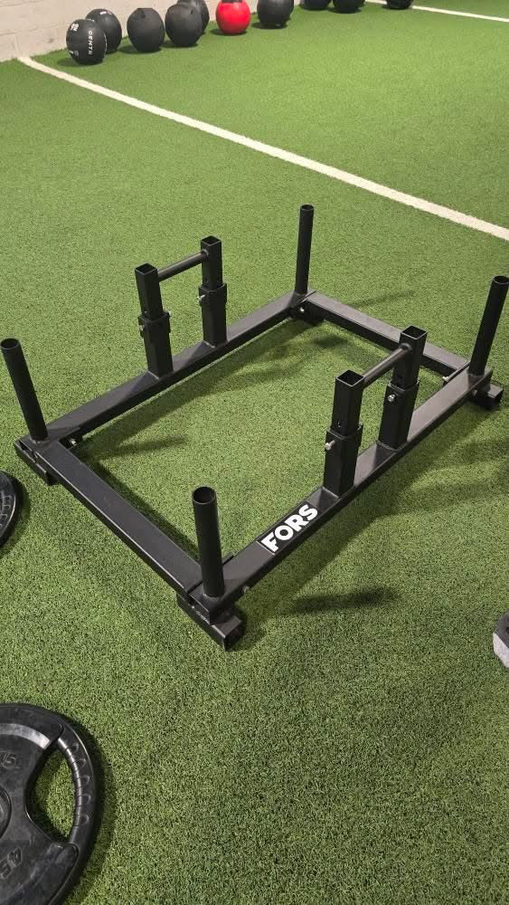 A FORS strongman frame and farmers carry implement on turf, showcasing heavy-duty strongman equipment used for strength and CrossFit training.